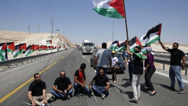 Palestinian protesters block the road during a protest along a highway leading to Khan al-Ahmar in support of its residents. (AFP/File)