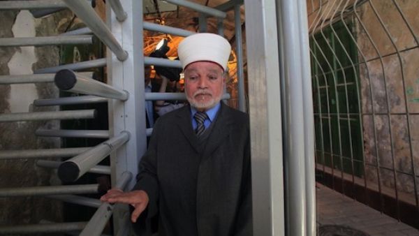 The Mufti of Jerusalem and Palestine, Sheikh Mohammed Hussein, passes through an iron gate as he crosses an Israeli checkpoint in the occupied West Bank city of Hebron. (AFP/ Hazem Bader) 
