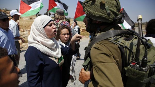 Demonstrators protest before Israeli forces West Bank village of Nabi Saleh, north of Ramallah, on May 12, 2017, after a demonstration following Friday prayers in solidarity with Palestinian prisoners on hunger strike in Israeli jails. (AFP/Abbas Momani)