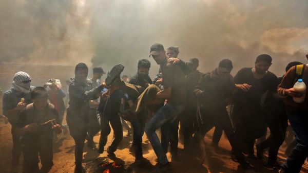 Palestinians carry a demonstrator injured during clashes with Israeli forces near the border between the Gaza strip and Israel east of Gaza City on May 14, 2018. (MAHMUD HAMS / AFP)