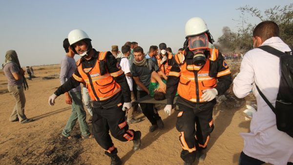 Palestinian medics evacuate a wounded protester during clashes with Israeli forces along the border with the Gaza strip east of Khan Yunis on May 18, 2018. (SAID KHATIB / AFP)