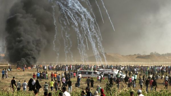 Palestinian protesters run for cover after Israeli forces launched tear gas canisters during a demonstration along the border on June 22, 2018. (MAHMUD HAMS/AFP)