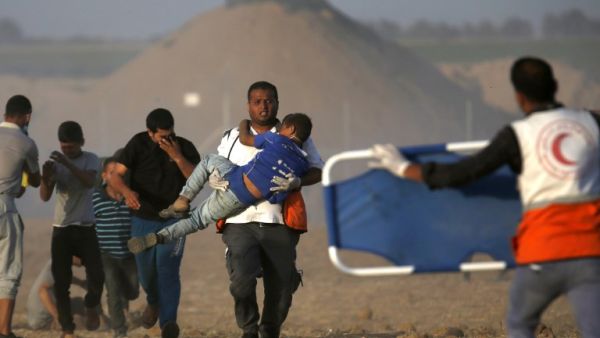 A Palestinian protester carries a child injured during a demonstration in front of Israeli forces along the border between the Gaza Strip and Israel, east of Khan Yunis in the southern Gaza Strip on June 22, 2018. (SAID KHATIB / AFP)