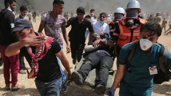 An injured Palestinian protestor is carried by fellow demonstrators during clashes with Israeli security forces near the border with Israel, east of Khan Yunis, in the southern Gaza Strip, on April 6, 2018 (AFP/SAID KHATIB)