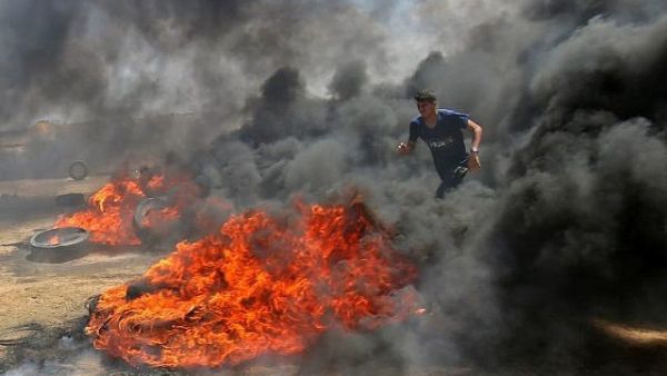 A Palestinian walks in the smoke billowing from burning tires during clashes with Israeli soldiers along border with Gaza strip east of Khan Younis, May 14, 2018 (AFP Photo/ Said Khatib) 