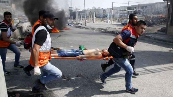 Palestinian medics carry away a protester who was injured during clashes with Israeli security forces in the West Bank city of Qalandiya, north of Jerusalem. (Abbas Momani/ AFP)
