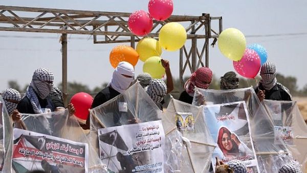 Palestinians load kites and balloons with flammable material in order to fly toward Israel, at the Israel-Gaza border in al-Bureij, central Gaza Strip, on June 14, 2018. (AFP Photo/ Mahmud Hams)