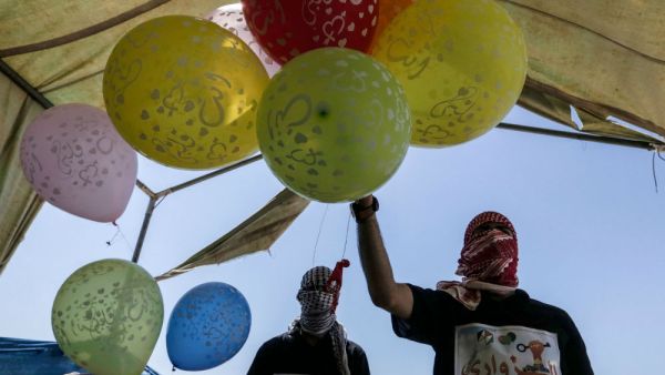 Palestinian protesters prepare kites loaded with flammable material to be flown towards Israel, at the Israel-Gaza border in al-Bureij, central Gaza Strip on June 14, 2018. (MAHMUD HAMS / AFP)
