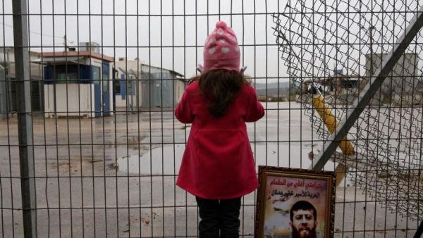 Maali, daughter of jailed Islamic Jihad spokesman Khader Adnan, stands next to a picture of her father outside a prison. (AFP/Abbas Momani)