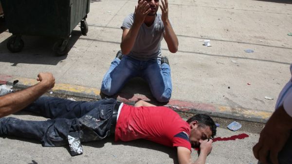 A man reacts next to the body of a young Palestinian protester shot dead on Thursday (Jaafar Ashtiyeh/AFP)