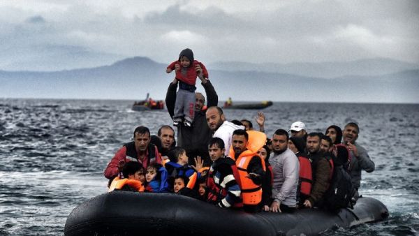 A man holds up a young boy as a boat carrying migrants and refugees arrives at the Greek island of Lesbos after crossing the Aegean sea from Turkey. (AFP Photo/Aris Messinis)