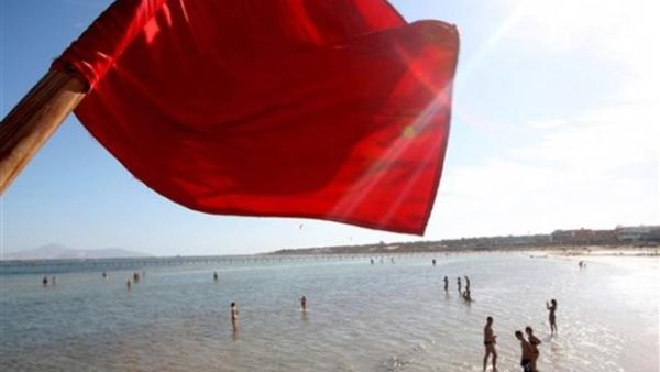 A red flag serving as a warning of shark sightings flutters over tourists enjoying a day on the beach in the Red Sea resort of Sharm el-Sheikh on December 8, 2010