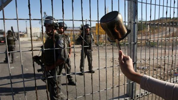 A protester waves a coffee pot at Israeli guards outside Ofer Prison. (AFP/File)