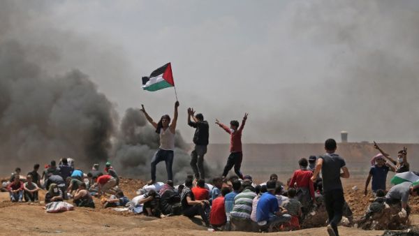 Palestinians wave their national flag as they demonstrate near the border between Israel and the Gaza Strip /AFP