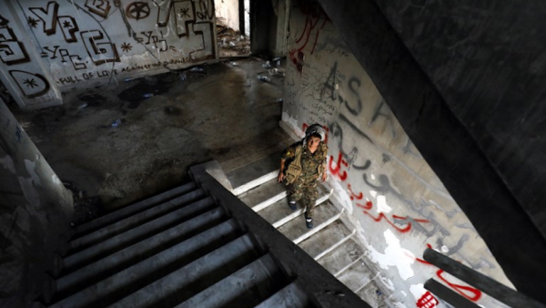 A female fighter from the Kurdish People's Protection Units (YPG) descends stairs in an abandoned building in Raqa's eastern al-Sanaa neighbourhood, on the edge of the old city, on August 13, 2017 / AFP