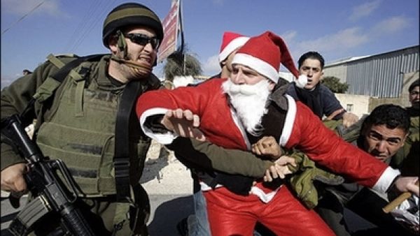 An Israeli soldier tackles a Palestinian protester dressed as Santa Claus or Father Christmas during at a protest against Israel’s separation barrier in the village of Umm Salamunah near the biblical West Bank town of Bethlehem. Israeli guards beat five demonstrators during the protest on Friday, organisers said.
Dec. 23, 2007 (AFP/Musa al-Shaer)