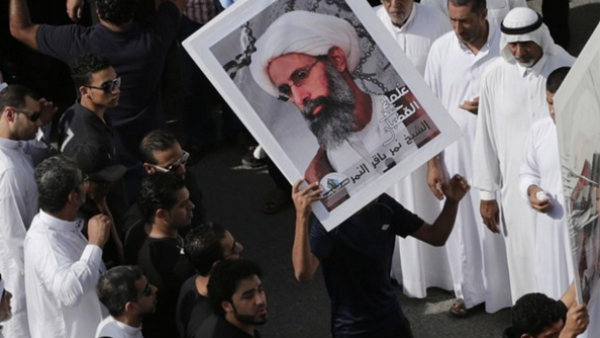 Protesters hold a sign featuring Sheikh Nimr al-Nimr. (Twitter)