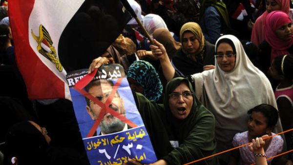 Opposition protesters shout slogans and show a defaced poster of their president as they gather in thousands at the Presidential Palace to protest against Egyptian President Mohamed Morsi and the Muslim Brotherhood (Source: AFP/GIANLUIGI GUERCIA)