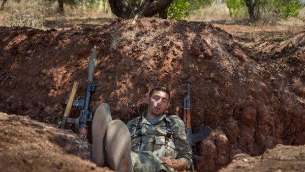 A rebel fighter takes a nap after his night shift in a trench along the highway that connects Idlib city with Latakia, 100m away from the Syrian regime's forces's positions, on July 15, 2013. (Source: AFP/DANIEL LEAL OLIVAS)