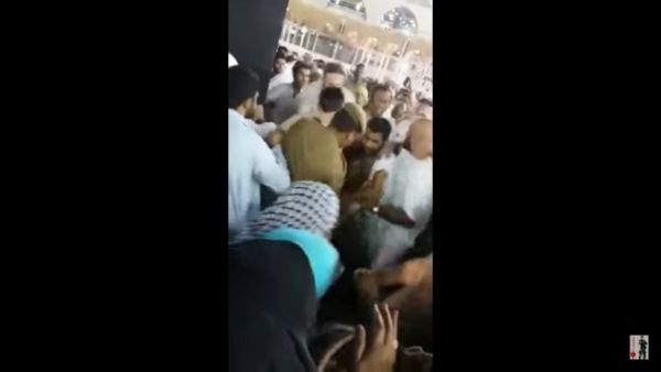 The man is rushed away from the Kaaba on Monday (screenshot)