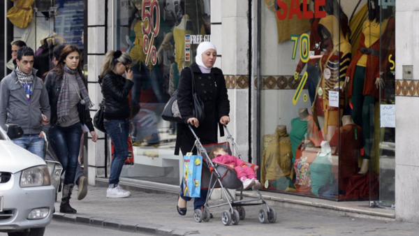 People walk past shop windows in Damascus. (AFP Photo / Louai Beshara)