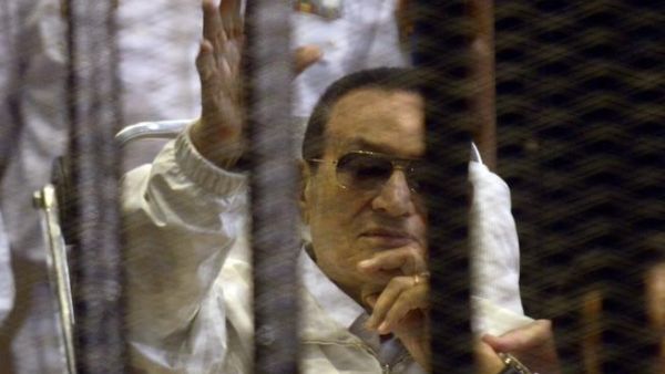Hosni Mubarak waves from his bed during his retrial which was quickly adjourned (AFP)