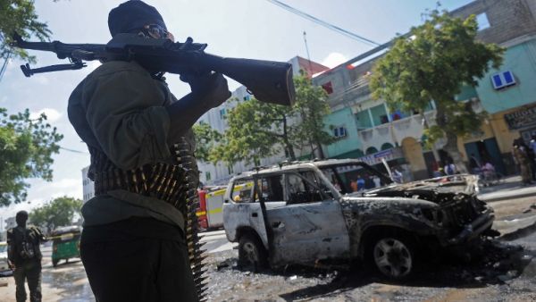 A Somali soldier patrols next to the remains of a car targeted in a bomb attack in Mogadishu on September 5, 2016. (AFP/Mohamed Abdiwahab)