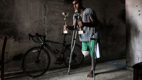 Palestinian cyclist Alaa Al-Daly, 21, who lost his leg by a bullet fired by Israeli troops along the Gaza border during a protest, stands next to his bicycle holding trophies he has won in competitions, at his home in Rafah in the southern Gaza Strip on April 19, 2018. Daly's dream of competing for Palestine at the Asian Games has been shattered after the athletes right leg was amputated after being shot by Israeli soldiers during recent demonstrations in Gaza.
SAID KHATIB / AFP