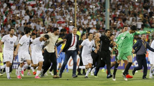 لاعبو منتخب إيران والمدرب كارلوس كيروش (وسط) يحتفلون بالتأهل