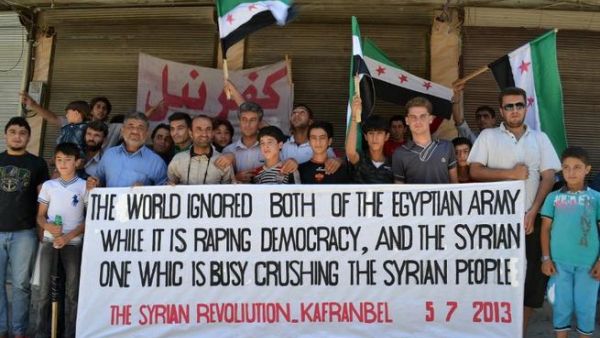  Syrian demonstrators posing with a banner referring to the situation in both Syria and Egypt during an anti-regime protest in Kfar Nubul in the northwestern province of Idlib (Shaam news network / AFP)