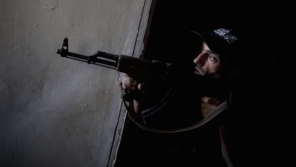 Syrian opposition fighter peers around a corner with weapon (AFP)