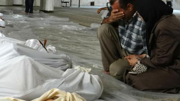 A handout image released by the Syrian opposition's Shaam News Network shows a Syrian couple mourning in front of bodies wrapped in shrouds ahead of funerals following what Syrian rebels claim to be a toxic gas attack by pro-government forces in eastern Ghouta, on the outskirts of Damascus on August 21, 2013. "AFP PHOTO / HO / SHAAM NEWS NETWORK" 