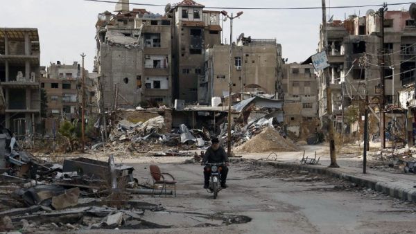A man drives his motorbike past damaged buildings on February 10, 2016 in Harasta, east of the Syrian capital Damascus. (AFP/Abdulmonam Eassa) A man drives his motorbike past damaged buildings on February 10, 2016 in Harasta, east of the Syrian capital Damascus. (AFP/Abdulmonam Eassa)