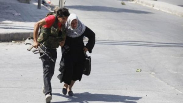 مقاتل من المعارضة يساعد عجوز على عبور شارع في حلب/ارشيف