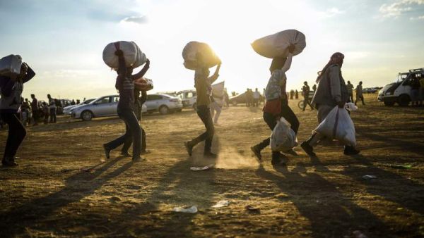 Displaced Syrian Kurds haul their personal belongings across the Syrian-Turkish border, September 2014.  (AFP/Bulent Kilic)
