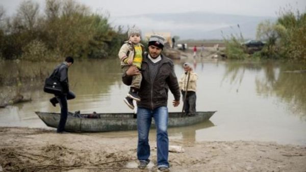 مواطن سوري يحمل طفله في جسر الشغور لاجئا الى تركيا/أ.ف.ب