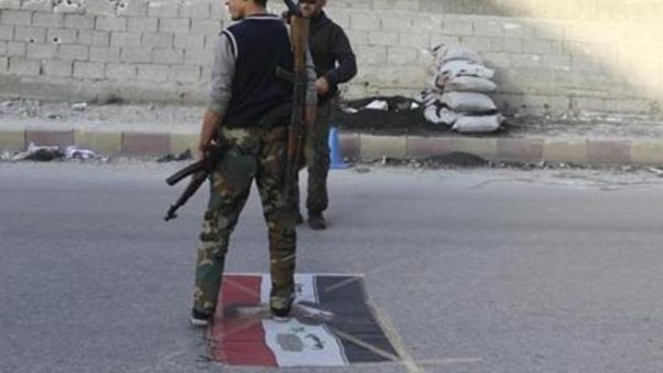 مقاتلون من المعارضة في سراقب يدوسون علما عليه صورة الرئيس السوري