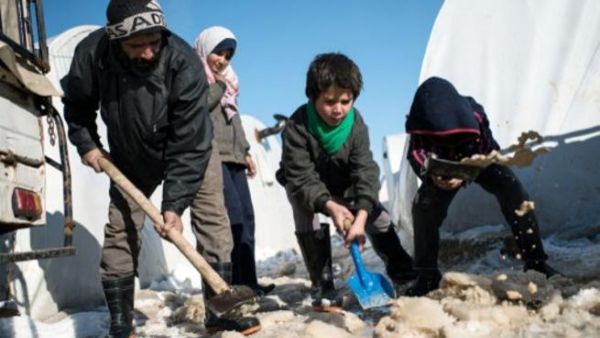 عائلة سورية تزيل الثلج من جوانب خيمتها في مخيم اعزاز شمالا/أ.ف.ب