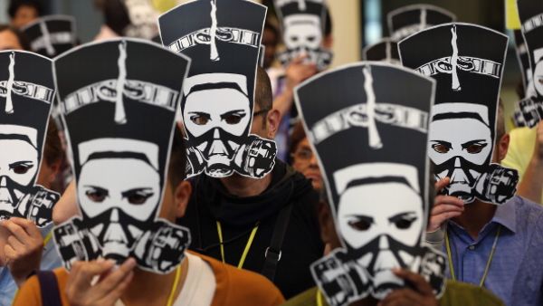 Delegates at a meeting of Amnesty International hold up masks depicting ancient Egyptian Queen Nefertiti wearing a gas mask in protest against the ongoing violence as well as sexual violence against women in Egypt on August 19, 2013. [ Getty Images]