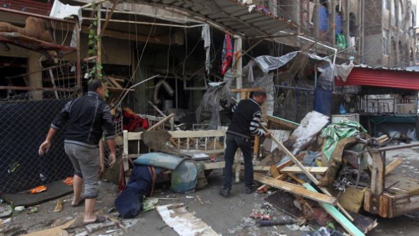 Iraqi men clean the rubble at the site of a blast that took place the previous day outside a cafe in Baghdad's Bayaa neighborhood on November 21, 2013. [Getty Images]