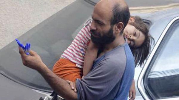 اللاجىء عبدالحليم العطار يحمل ابنته على كتفه خلال بيعه للأقلام