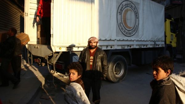 A Syrian man poses in front of a lorry of the Syrian Arab Red Crescent containing aid parcels upon its arrival on February 13, 2016 in the rebel-held city of Douma, northeast of the capital Damascus. (AFP/Abd Doumany)