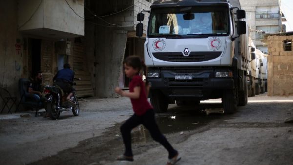 A convoy of Syrian Red Crescent trucks carrying aid drives through Erbin, a besieged rebel-held town east of the Syrian capital Damascus, on June 29, 2016. 