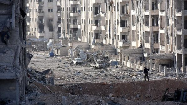 A member of the Syrian pro-government forces stands amid heavily damaged buildings in Aleppo's 1070 district on November 8, 2016, after troops seized it from rebel fighters. (AFP/Georges Ourfalian)