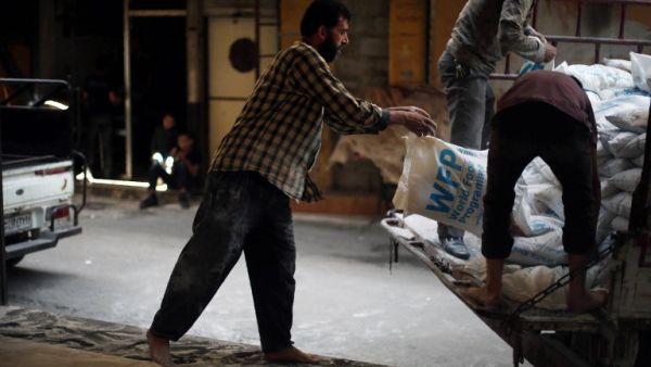 Syrian men load aid parcels provided by the UN World Food Program (WFP) and the Syrian Arab Red Crescent into a truck for food distribution on May 11, 2016, in the rebel-held village of Saqba, nearl Damascus. (AFP/Amer al-Mohibany)