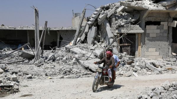 A Syrian man rides his motorcycle past collapsed buildings in the northern Syrian town of Manbij as civilians go back to their homes on August 14, 2016. (AFP/Delil Souleilman)