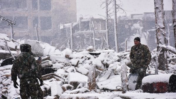 Syrian pro-government forces walk as snow falls in Aleppo on December 21, 2016. (AFP/George Ourfalian)