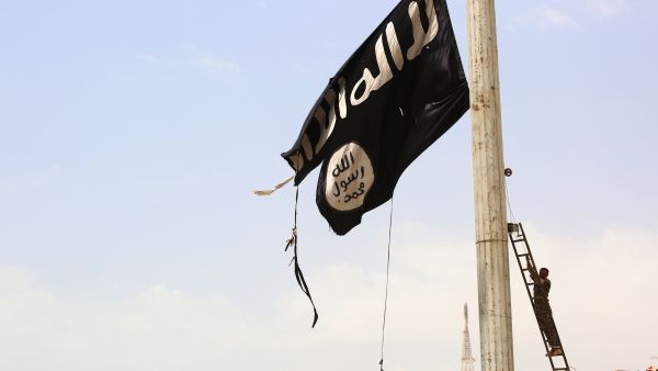A member of the Syrian Democratic Forces removes a Daesh flag from an area in the Syrian city of Tabqa recently recaptured from them. (AFP/Delil Souleiman)