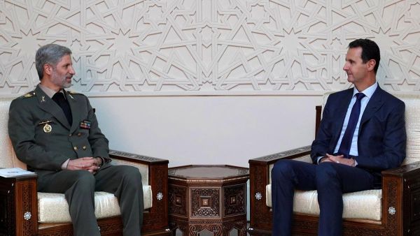 Iranian defence minister Amir Hatami, left, meets with Syrian president Bashar Al Assad in Damascus. (SANA/AFP)