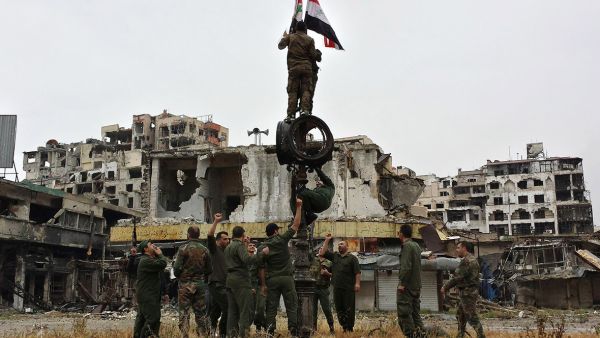 Syrian government fighters raise the country's flag after a previous evacuation of opposition fighters in 2014. (AFP)  